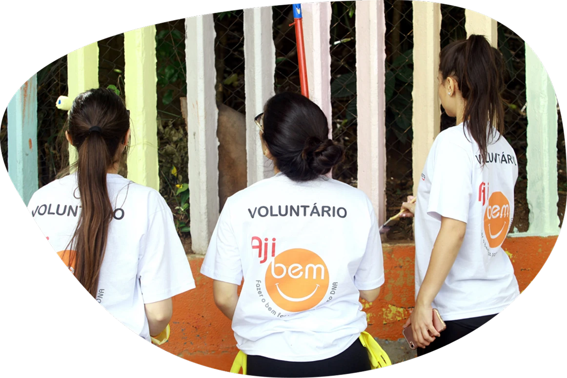 Voluntários de costas mostrando a camiseta do projeto