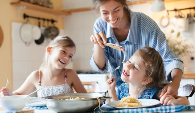 Mãe comendo macarrão com suas filhas