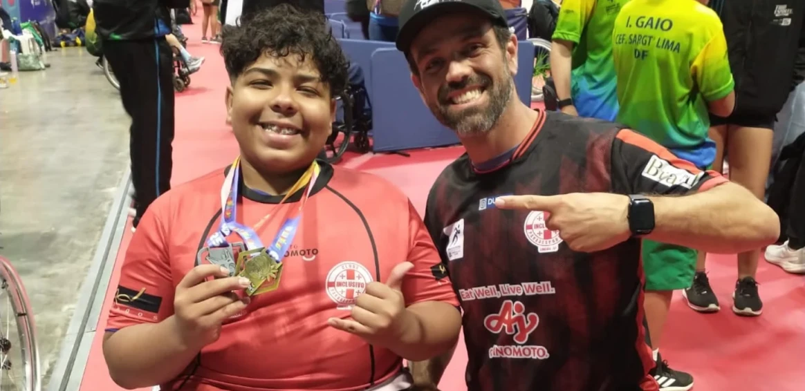 Atleta medalhista com seu instrutor ao lado