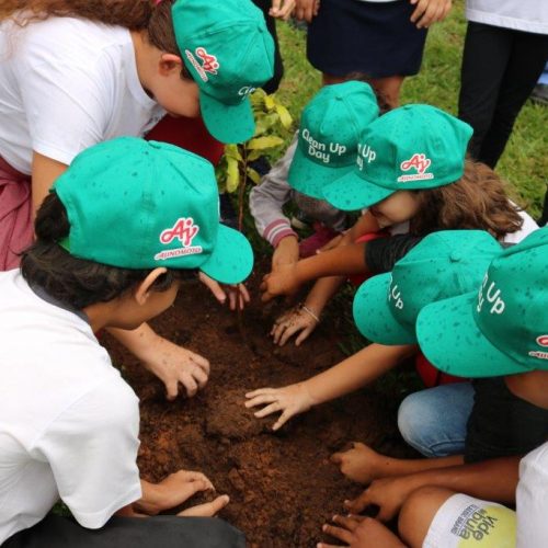 Grupo de crianças com boné Ajibem mexendo na terra