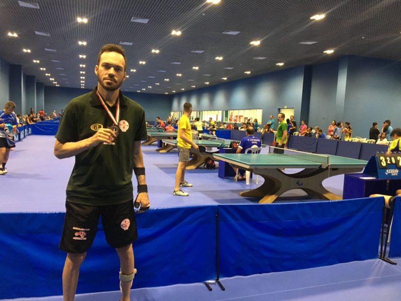 Homem atleta posa para foto com a medalha em mãos